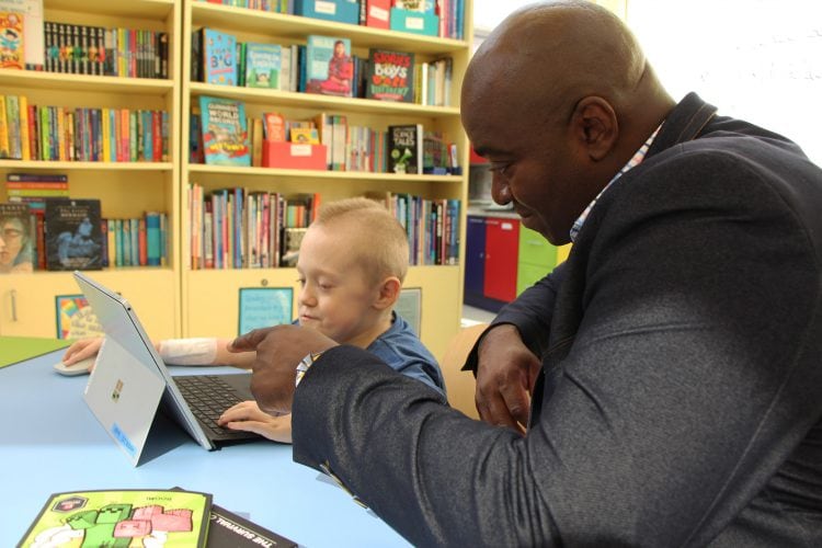 A man helps a child on a Microsoft Surface Pro laptop
