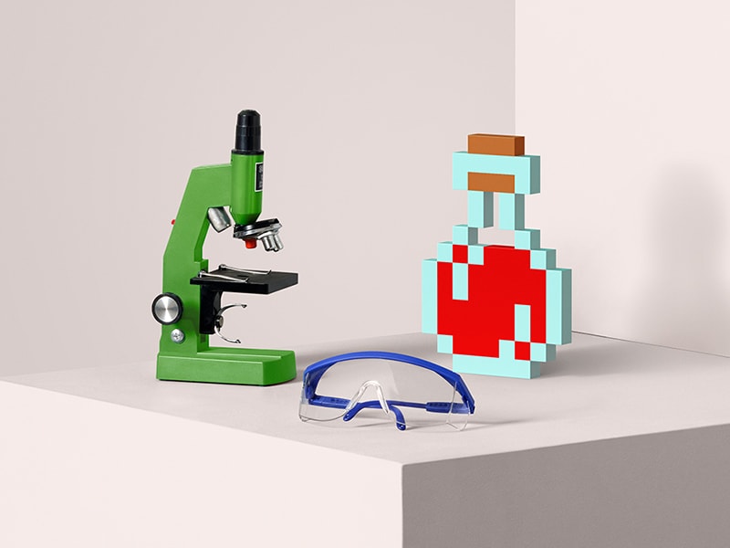 A microscope, some safety goggles, and a Minecraft potion sit on a table