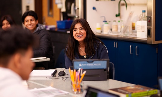 A student smiling in front of a laptop in science class