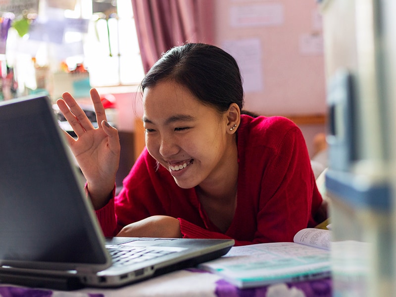A smiling female student uses a laptop computer in her studies